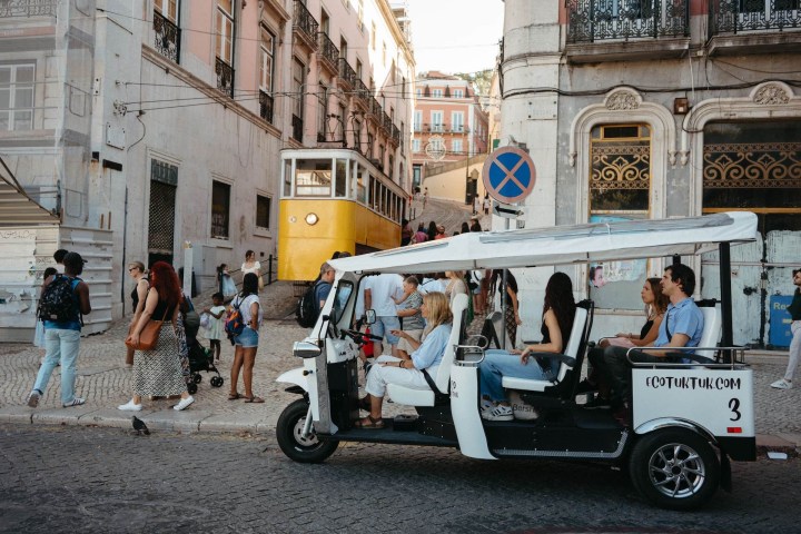 a group of people riding on the back of a tuk tuk in Lisboa