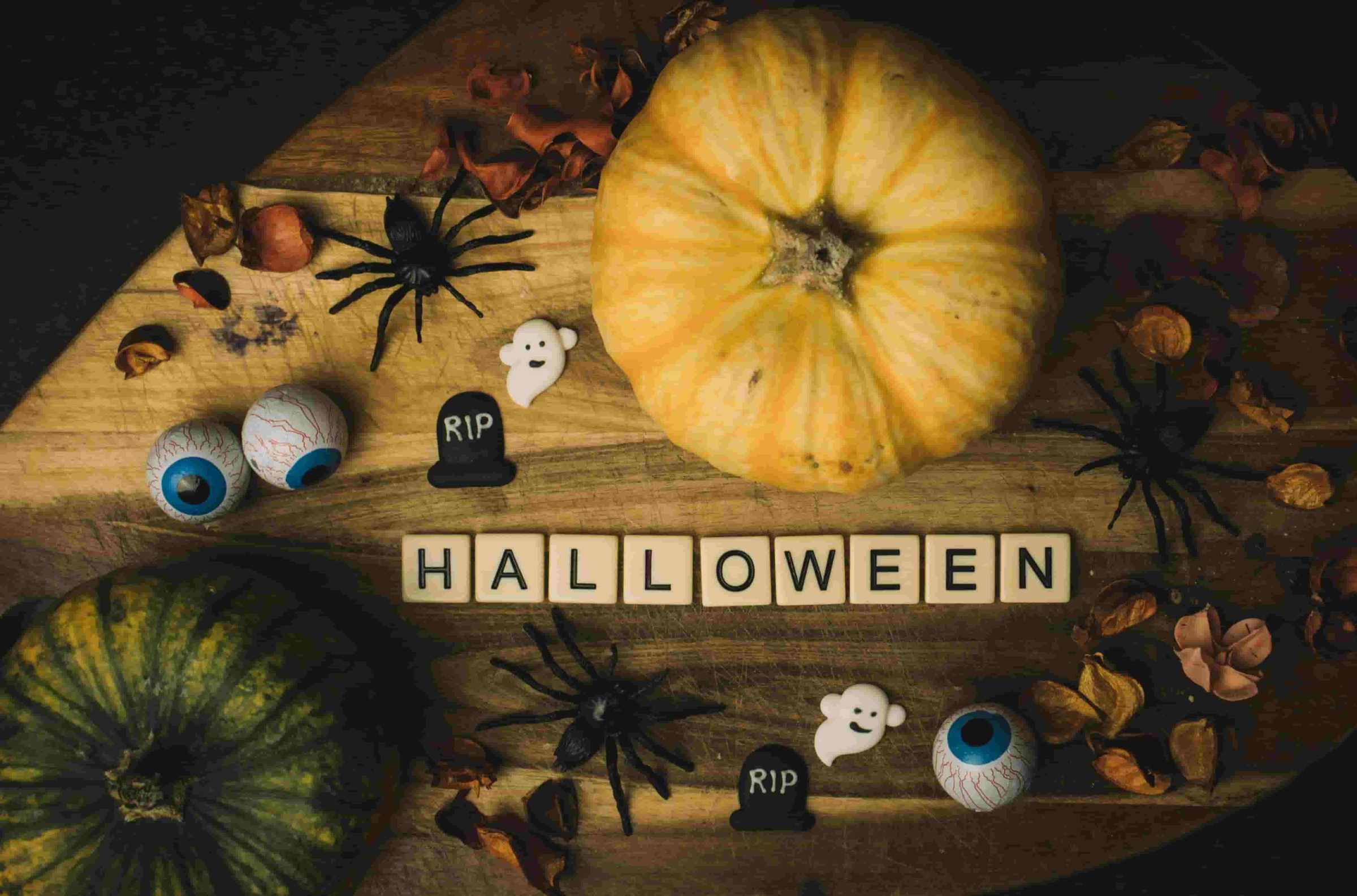 Halloween Madrid Halloween decorations with pumpkins, spiders, eyes, RIP gravestones, and ghost on a wooden board.