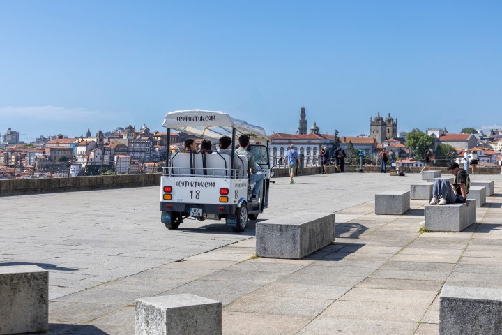 Electric tour cart on a paved area with cityscape in the background.